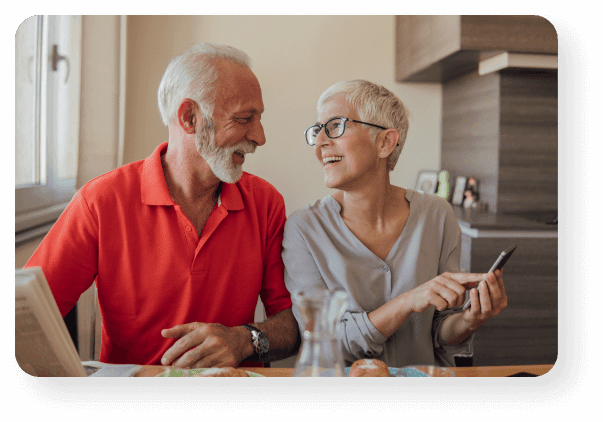 A Retired Couple Discussing Annuity Rates Looking At A Mobile Phone